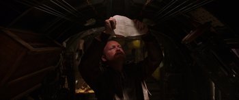 Movie still from “Shadow in the Cloud” (2020), directed by Roseanne Liang – A man holding a sheet of paper up to the ceiling of a room; Close Up shot, Low angle
