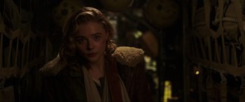 Movie still from “Shadow in the Cloud” (2020), directed by Roseanne Liang – A woman in a brown jacket standing in a dark room; Close Up shot, Over the shoulder angle