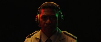 Movie still from “Shadow in the Cloud” (2020), directed by Roseanne Liang – A man wearing headphones and a suit; Close Up shot, Over the shoulder angle