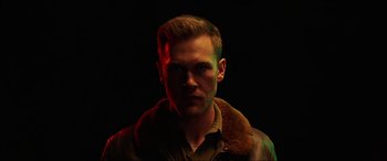 Movie still from “Shadow in the Cloud” (2020), directed by Roseanne Liang – A man in a brown jacket is looking at the camera; Close Up shot, Low angle