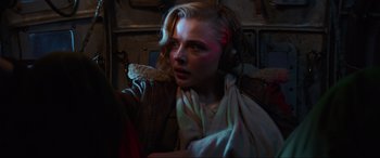 Movie still from “Shadow in the Cloud” (2020), directed by Roseanne Liang – A woman with blonde curly hair wearing headphones; Close Up shot, Low angle