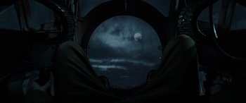 Movie still from “Shadow in the Cloud” (2020), directed by Roseanne Liang – A view of the moon through a porthole of an airplane; Wide shot, Overhead angle