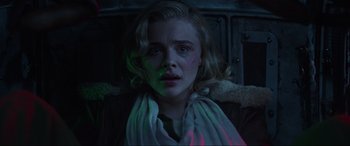 Movie still from “Shadow in the Cloud” (2020), directed by Roseanne Liang – A woman with blonde curly hair is sitting in a dark room; Close Up shot, Low angle