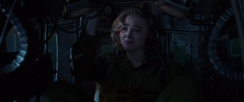 Movie still from “Shadow in the Cloud” (2020), directed by Roseanne Liang – A woman with blonde curly hair is in the dark; Medium shot, High angle