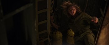 Movie still from “Shadow in the Cloud” (2020), directed by Roseanne Liang – A woman in a dark room next to a fire hydrant; Medium shot, Low angle