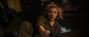 Movie still from “Shadow in the Cloud” (2020), directed by Roseanne Liang – A young woman with blonde curly hair holding a knife in her hand; Close Up shot, Over the shoulder angle