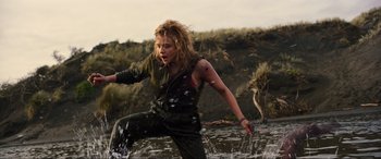 Movie still from “Shadow in the Cloud” (2020), directed by Roseanne Liang – A woman is running through the water in a field; Medium shot, Low angle