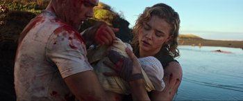 Movie still from “Shadow in the Cloud” (2020), directed by Roseanne Liang – A man and a woman are holding a baby; Close Up shot, High angle