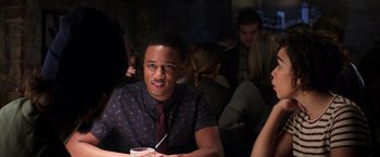 Movie still from “Shaft” (2019), directed by Tim Story – A man sitting at a table in front of a group of people; Medium shot, Over the shoulder angle