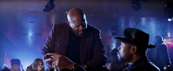 Movie still from “Shaft” (2019), directed by Tim Story – A man in a suit talking to another man in a hat; Medium shot, Over the shoulder angle
