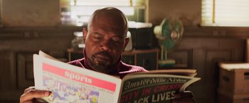 Movie still from “Shaft” (2019), directed by Tim Story – A man sitting down reading a newspaper in front of a fan; Close Up shot, Over the shoulder angle