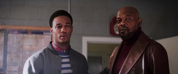 Movie still from “Shaft” (2019), directed by Tim Story – Two men standing next to each other in front of a brick wall; Medium shot, Over the shoulder angle