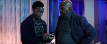 Movie still from “Shaft” (2019), directed by Tim Story – Two men are looking at a cell phone together; Medium shot, Over the shoulder angle