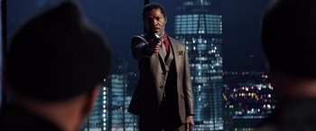 Movie still from “Shaft” (2019), directed by Tim Story – A man in a suit and tie holding a gun; Medium shot, Over the shoulder angle