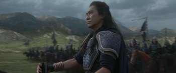 Movie still from “Shang-Chi and the Legend of the Ten Rings” (2021), directed by Destin Daniel Cretton – A man in a black and blue outfit is looking to the side; Medium shot, Low angle