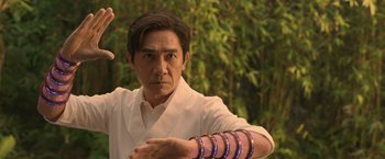 Movie still from “Shang-Chi and the Legend of the Ten Rings” (2021), directed by Destin Daniel Cretton – A man in a white shirt and a purple bracelet; Close Up shot, Low angle