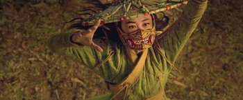Movie still from “Shang-Chi and the Legend of the Ten Rings” (2021), directed by Destin Daniel Cretton – A person with a mask and a umbrella on their head; Close Up shot, Low angle