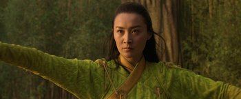 Movie still from “Shang-Chi and the Legend of the Ten Rings” (2021), directed by Destin Daniel Cretton – A woman in a green and yellow outfit is standing in front of a tree; Close Up shot, Low angle