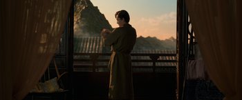 Movie still from “Shang-Chi and the Legend of the Ten Rings” (2021), directed by Destin Daniel Cretton – A man in a robe standing in front of a mountain range; Medium shot, Over the shoulder angle