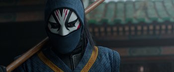 Movie still from “Shang-Chi and the Legend of the Ten Rings” (2021), directed by Destin Daniel Cretton – A person with a mask and a sword in their hands; Close Up shot, Low angle