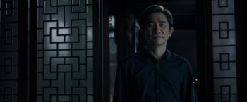 Movie still from “Shang-Chi and the Legend of the Ten Rings” (2021), directed by Destin Daniel Cretton – A man in a black shirt standing in front of a brick wall; Close Up shot, Low angle