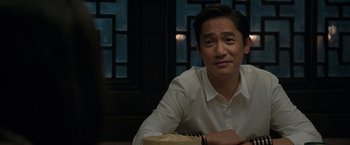 Movie still from “Shang-Chi and the Legend of the Ten Rings” (2021), directed by Destin Daniel Cretton – A person sitting at a table; Close Up shot, Over the shoulder angle