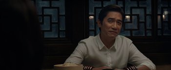 Movie still from “Shang-Chi and the Legend of the Ten Rings” (2021), directed by Destin Daniel Cretton – A man sitting at a table in front of a window; Close Up shot, Over the shoulder angle