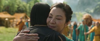 Movie still from “Shang-Chi and the Legend of the Ten Rings” (2021), directed by Destin Daniel Cretton – A woman hugging another woman outside in the sun; Close Up shot, Over the shoulder angle