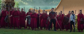 Movie still from “Shang-Chi and the Legend of the Ten Rings” (2021), directed by Destin Daniel Cretton – A group of people dressed in red and holding sticks in their hands; Wide shot, Low angle