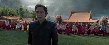 Movie still from “Shang-Chi and the Legend of the Ten Rings” (2021), directed by Destin Daniel Cretton – A man standing in front of a group of people; Medium shot, Over the shoulder angle