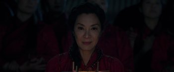 Movie still from “Shang-Chi and the Legend of the Ten Rings” (2021), directed by Destin Daniel Cretton – A woman in a red dress is smiling for the camera; Close Up shot, Over the shoulder angle