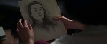 Movie still from “Shang-Chi and the Legend of the Ten Rings” (2021), directed by Destin Daniel Cretton – A person holding a drawing of a woman's face; Extreme Close Up shot, Over the shoulder angle