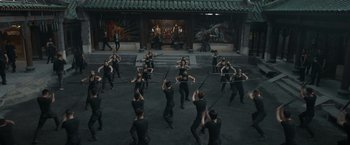 Movie still from “Shang-Chi and the Legend of the Ten Rings” (2021), directed by Destin Daniel Cretton – A group of people are practicing martial arts in a courtyard; Wide shot, High angle
