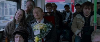 Movie still from “Shaun of the Dead” (2004), directed by Edgar Wright – A man sitting on a bus holding a bouquet of flowers; Medium shot, Over the shoulder angle