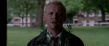 Movie still from “Shaun of the Dead” (2004), directed by Edgar Wright – A man in a suit and tie holding a plant in front of his face; Close Up shot, Low angle