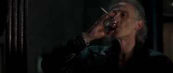 Movie still from “Shaun of the Dead” (2004), directed by Edgar Wright – A man in a leather jacket is drinking whiskey and smoking a cigarette; Close Up shot, Low angle