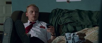 Movie still from “Shaun of the Dead” (2004), directed by Edgar Wright – A man sitting on a couch holding a cell phone; Medium shot, High angle