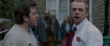 Movie still from “Shaun of the Dead” (2004), directed by Edgar Wright – A group of people standing next to each other on the street; Medium shot, Over the shoulder angle