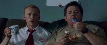 Movie still from “Shaun of the Dead” (2004), directed by Edgar Wright – Two men sitting on a couch eating a cupcake; Medium shot, Overhead angle
