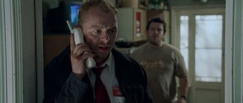 Movie still from “Shaun of the Dead” (2004), directed by Edgar Wright – A man in a red tie talking on a phone; Close Up shot, Over the shoulder angle