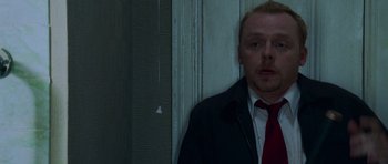 Movie still from “Shaun of the Dead” (2004), directed by Edgar Wright – A man wearing a suit and tie standing in front of a door; Close Up shot, Low angle