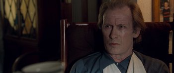 Movie still from “Shaun of the Dead” (2004), directed by Edgar Wright – An older man sitting in a chair looking at the camera; Close Up shot, High angle