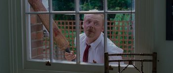 Movie still from “Shaun of the Dead” (2004), directed by Edgar Wright – A man holding a bat looking out of a window; Medium shot, Over the shoulder angle
