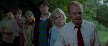 Movie still from “Shaun of the Dead” (2004), directed by Edgar Wright – A group of people standing next to each other in a forest; Medium shot, Over the shoulder angle