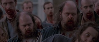 Movie still from “Shaun of the Dead” (2004), directed by Edgar Wright – A group of people that are standing in the street; Close Up shot, Over the shoulder angle