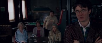 Movie still from “Shaun of the Dead” (2004), directed by Edgar Wright – A group of people sitting at a table in front of a pool table; Medium shot, Over the shoulder angle