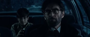 Movie still from “Shazam!” (2019), directed by David F. Sandberg – A man in a suit and glasses sitting in a car; Close Up shot, Over the shoulder angle