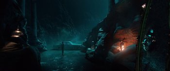 Movie still from “Shazam!” (2019), directed by David F. Sandberg – A man standing in a cave with a car in the background; Extreme Wide shot, High angle