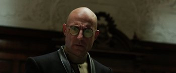 Movie still from “Shazam!” (2019), directed by David F. Sandberg – A bald man wearing glasses and a black jacket; Close Up shot, Low angle