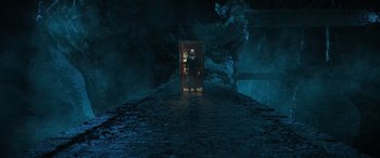 Movie still from “Shazam!” (2019), directed by David F. Sandberg – A person standing in front of an open door in a cave; Wide shot, High angle